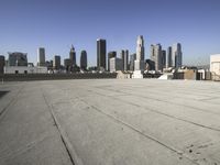 a wide view of a city skyline and a man with a skateboard in the foreground