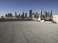 a wide view of a city skyline and a man with a skateboard in the foreground