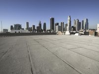 a wide view of a city skyline and a man with a skateboard in the foreground