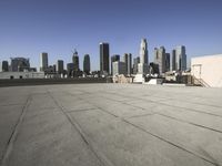 a wide view of a city skyline and a man with a skateboard in the foreground