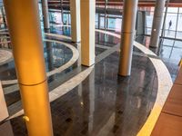 a building with many pillars standing in a circle on tiled floors and flooring that has a person walking down one side