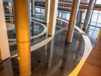 a building with many pillars standing in a circle on tiled floors and flooring that has a person walking down one side