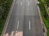 a highway with several empty lanes next to trees and buildings of various sizes are shown