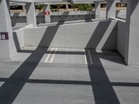 empty parking garage with multiple white pillars and ceiling beams and overhead parking space for car parked