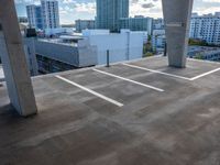 a parking lot with a view of downtown buildings in the distance behind it and one building painted white on the left