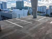 a parking lot with a view of downtown buildings in the distance behind it and one building painted white on the left