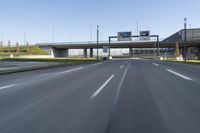 a bridge over an empty city highway with a car and truck travelling by it on the highway