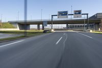 a bridge over an empty city highway with a car and truck travelling by it on the highway