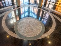 large marble floor in a lobby with windows in the background and an open space to showcase other buildings