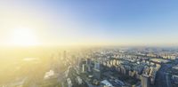 the city skyline is covered with skyscrapers and buildings, a yellow sunset illuminates the sunlight