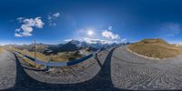 two fisheye shots show the view from across the street in front of mountains, and the sun shining down on the mountain range