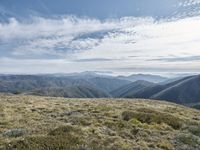 the person is standing on top of a mountain, with the sky above them and a green valley below