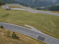 a car is driving on an empty road near a hill with trees and mountains in the distance