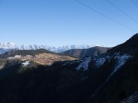 the view of mountains from the top of a mountain with cable car tracks and cable