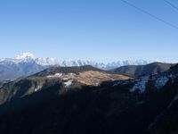 the view of mountains from the top of a mountain with cable car tracks and cable