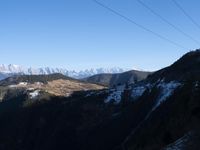 the view of mountains from the top of a mountain with cable car tracks and cable