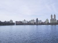 a view of the city from a distance from a lake in central park, new york