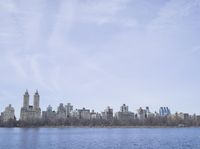 a view of the city from a distance from a lake in central park, new york