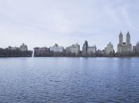 a view of the city from a distance from a lake in central park, new york