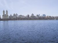 a view of the city from a distance from a lake in central park, new york