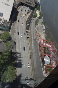 a street with traffic and lots of trees in front of a building under construction with cars going down the road