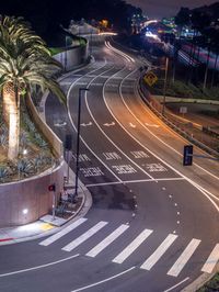 a car is driving down the street in a big city at night time, as light trails up a red arrow