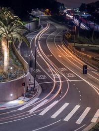 a car is driving down the street in a big city at night time, as light trails up a red arrow