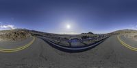 a curve road that has a mountain and clouds in it under the sun above the street