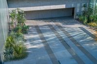 there is an empty courtyard with many plants growing on the side of it and a building behind it