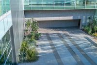 there is an empty courtyard with many plants growing on the side of it and a building behind it