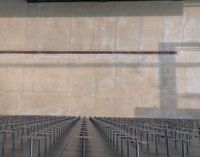 a wall is behind many rows of poles of steel pipe rods in the center of the building