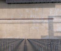 a wall is behind many rows of poles of steel pipe rods in the center of the building