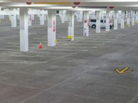large parking garage with a few cars in it, and some cones are on the ground
