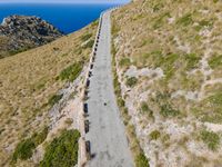 paved walkway on mountain above a grassy cliff and ocean views over the water as seen from the top