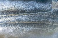 an aerial view of a person on a surfboard riding waves in the ocean waters