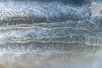 an aerial view of a person on a surfboard riding waves in the ocean waters