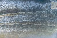 an aerial view of a person on a surfboard riding waves in the ocean waters