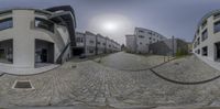 the photo shows a 360 - lens image of two buildings and one street that is circular