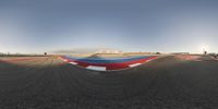 a view of an open race track from a fish eye lens in midair with a person riding a motorcycle