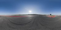 a camera - controlled view of a racing track and field and the setting sun on a clear blue sky