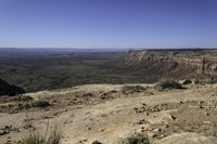 a view of a large valley at the top of some mountains with a distant area below