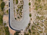 an aerial view of a road through the hills in the desert with bushes and shrubs growing along the side