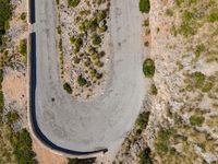 an aerial view of a road through the hills in the desert with bushes and shrubs growing along the side