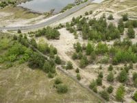 aerial view of large open country road between trees and sand dunes above river, near roadway in scenic rural area