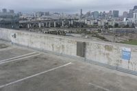 a car park with parking spaces and view of a city in the distance on a cloudy day