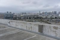 a car park with parking spaces and view of a city in the distance on a cloudy day