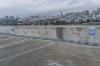 a car park with parking spaces and view of a city in the distance on a cloudy day