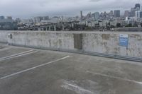 a car park with parking spaces and view of a city in the distance on a cloudy day
