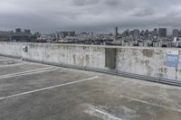 a car park with parking spaces and view of a city in the distance on a cloudy day