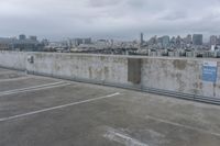 a car park with parking spaces and view of a city in the distance on a cloudy day